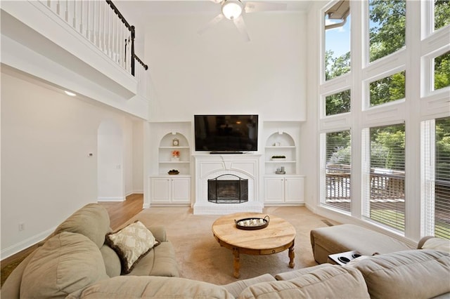 4108 Wyndam Hill Dr, Suwanee, GA 30024 - living room with a towering ceiling, arched walkways, built in shelves, ceiling fan, and a fireplace