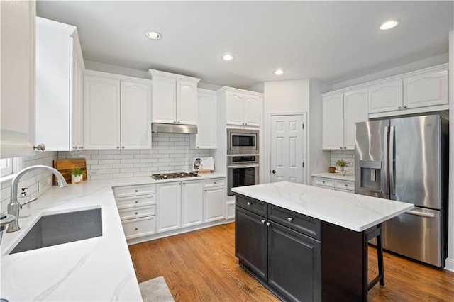 4108 Wyndam Hill Dr, Suwanee, GA 30024 - kitchen with stainless steel appliances, white cabinetry, tasteful backsplash, a kitchen breakfast bar, and under cabinet range hood