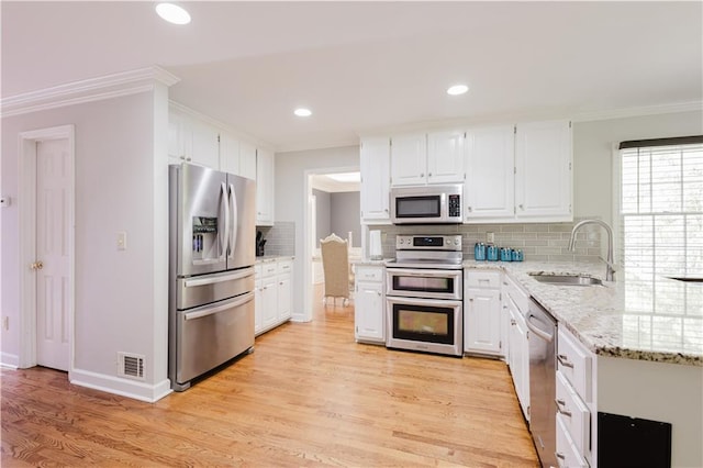 kitchen with crown molding, appliances with stainless steel finishes, white cabinetry, a sink, and light wood-type flooring