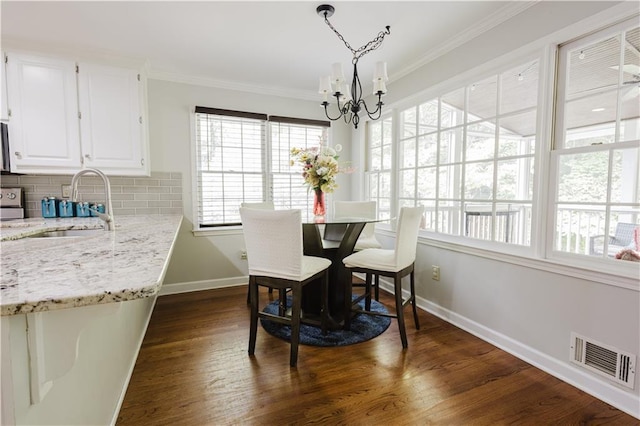 dining room featuring crown molding, dark wood-style flooring, visible vents, baseboards, and an inviting chandelier