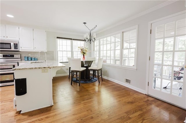 kitchen featuring crown molding, tasteful backsplash, white microwave, white cabinets, and double oven range