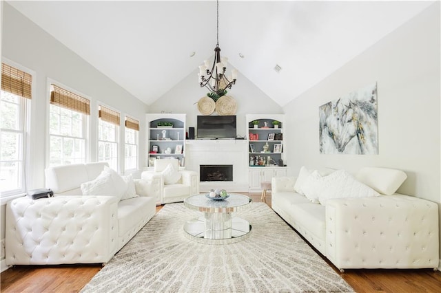 living area featuring a notable chandelier, a fireplace, wood finished floors, and a healthy amount of sunlight