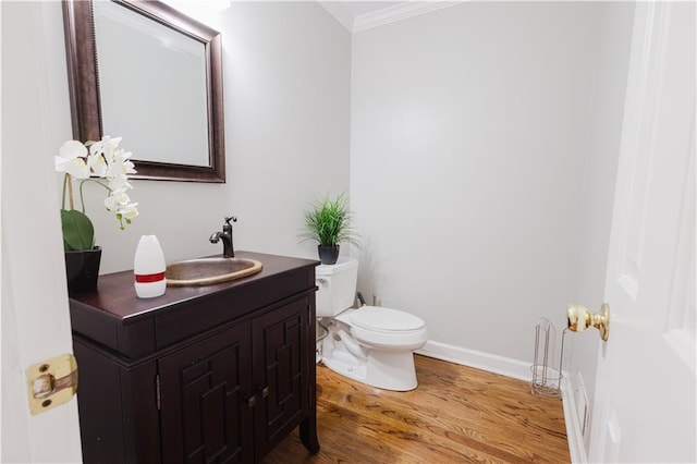 bathroom featuring baseboards, toilet, wood finished floors, crown molding, and vanity