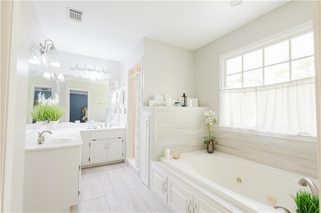 full bathroom featuring a jetted tub, visible vents, and vanity