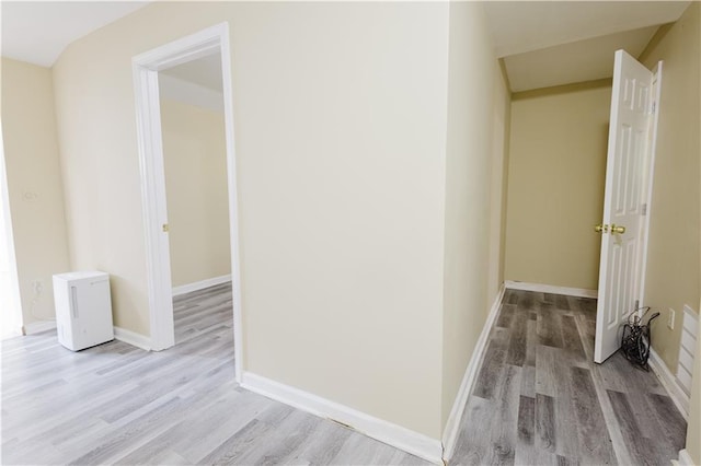 corridor featuring light wood finished floors and baseboards