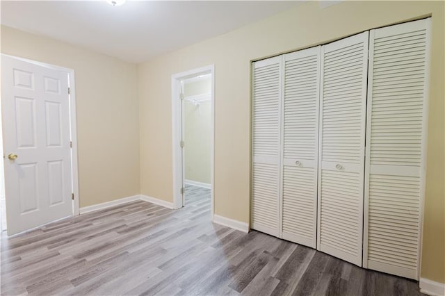 unfurnished bedroom featuring baseboards, a closet, and wood finished floors