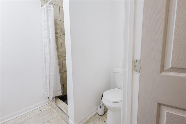 bathroom with tile patterned flooring, a shower stall, toilet, and baseboards