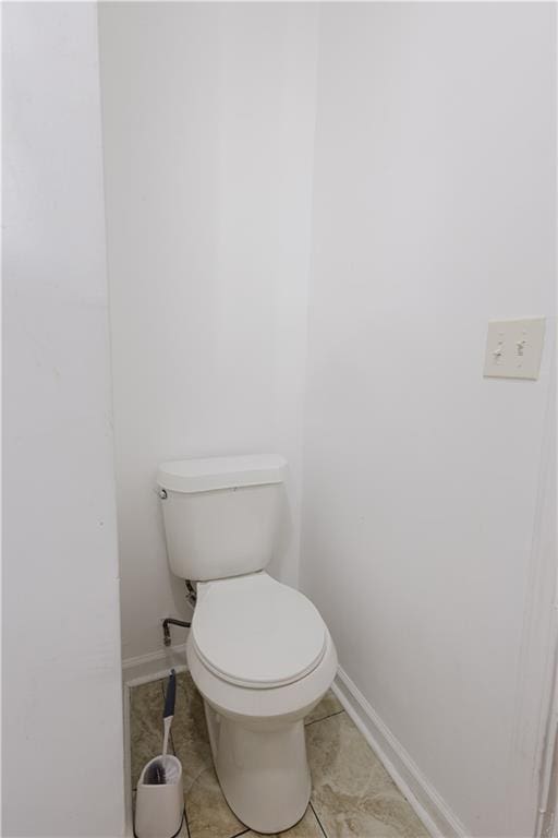 bathroom with toilet, baseboards, and tile patterned floors