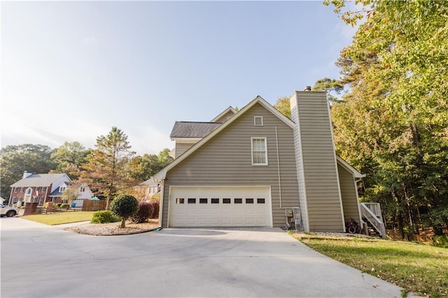 view of home's exterior featuring a garage, driveway, and a chimney