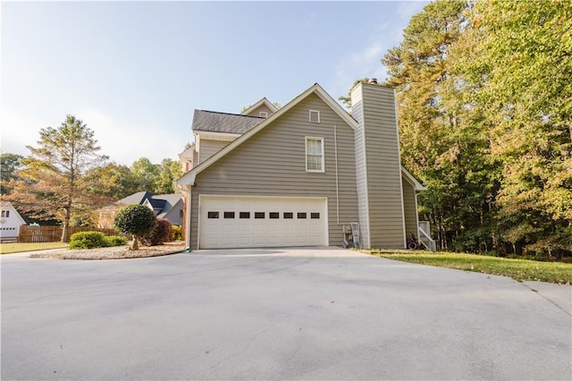 view of side of property with a chimney, fence, and concrete driveway