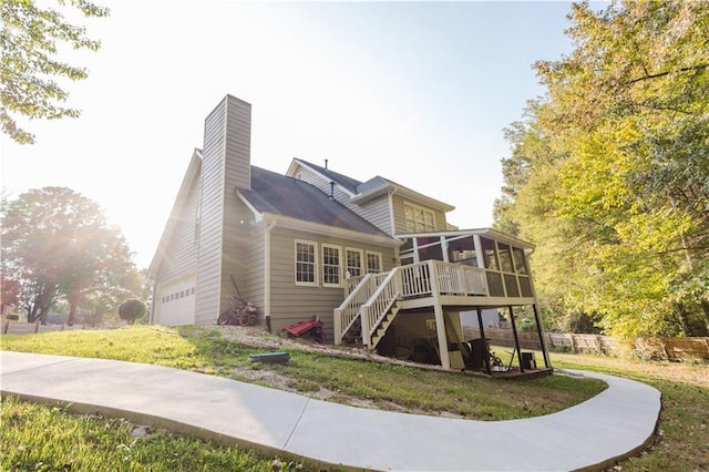 rear view of house featuring a garage, a sunroom, a chimney, stairway, and fence