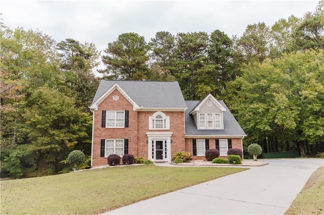 colonial house featuring a front lawn and brick siding