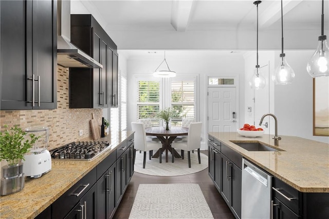 kitchen featuring pendant lighting, stainless steel appliances, sink, and wall chimney range hood