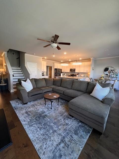 living area with ornamental molding, a ceiling fan, stairway, and dark wood-style floors