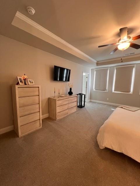 bedroom featuring baseboards, a raised ceiling, light colored carpet, ceiling fan, and ornamental molding