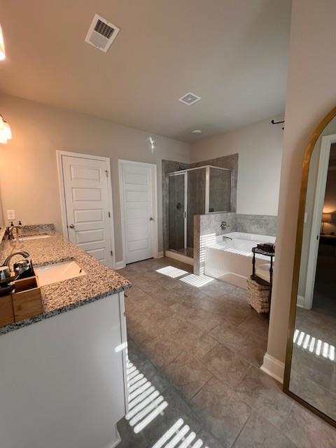 bathroom featuring a sink, visible vents, a bath, double vanity, and a stall shower