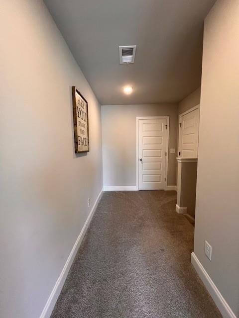 corridor with carpet floors, visible vents, and baseboards