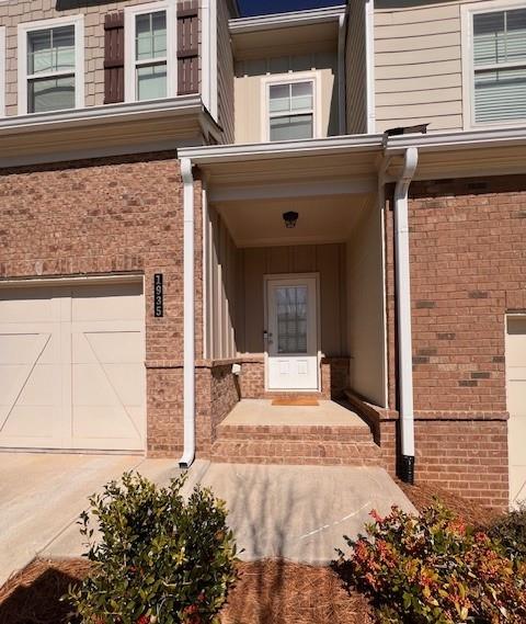 property entrance featuring a garage, concrete driveway, and brick siding