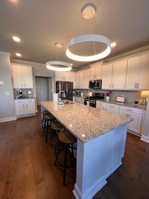 kitchen featuring dark wood-style floors, stainless steel appliances, decorative backsplash, white cabinets, and a sink