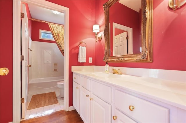 full bathroom with hardwood / wood-style flooring, vanity,  shower combination, and toilet