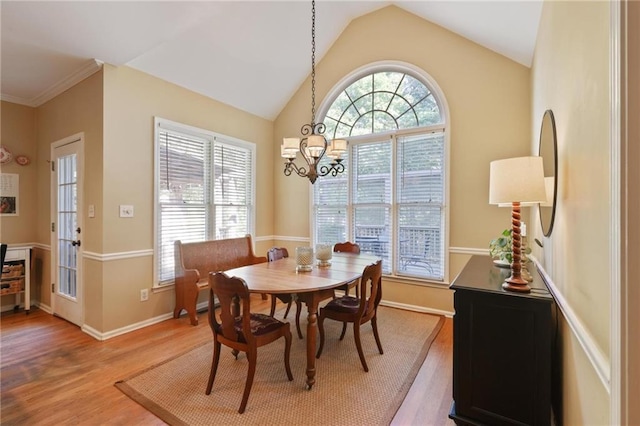 dining area with a wealth of natural light, wood-type flooring, and an inviting chandelier