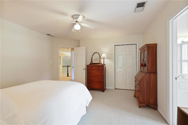 bedroom with ceiling fan, light colored carpet, and ensuite bathroom