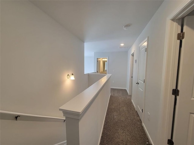 corridor with visible vents, dark carpet, an upstairs landing, and baseboards