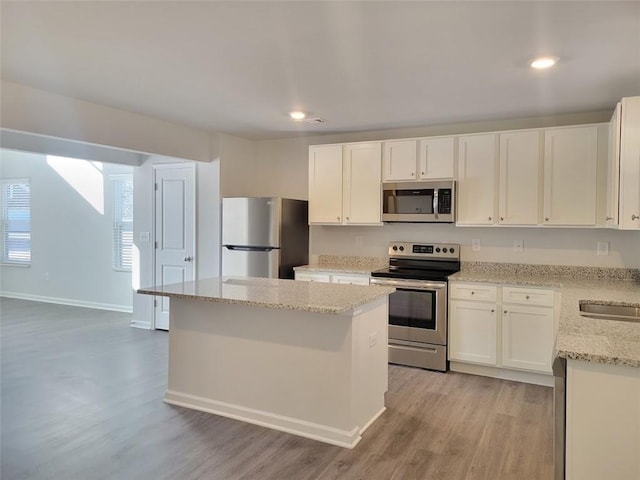 kitchen with stainless steel appliances, a kitchen island, and white cabinetry