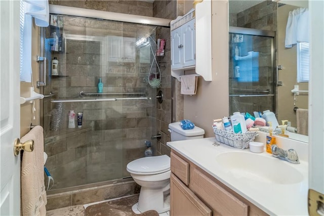 bathroom featuring vanity, toilet, and a shower with shower door