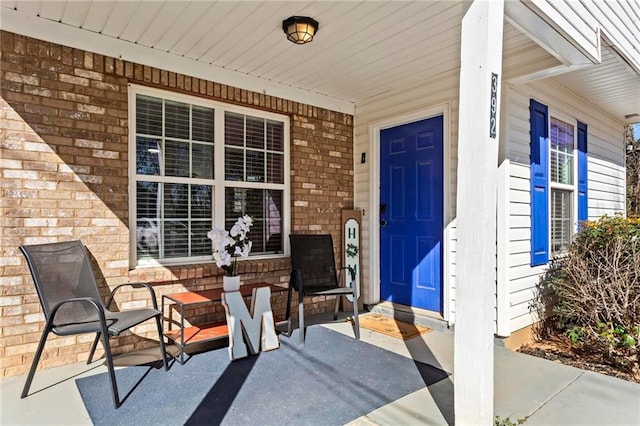 property entrance featuring a porch and brick siding