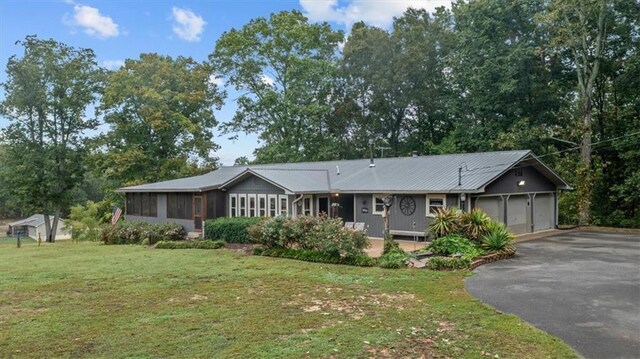 single story home with a garage, a sunroom, aphalt driveway, and a front yard