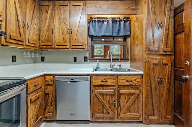 kitchen featuring light countertops, appliances with stainless steel finishes, a sink, and brown cabinets