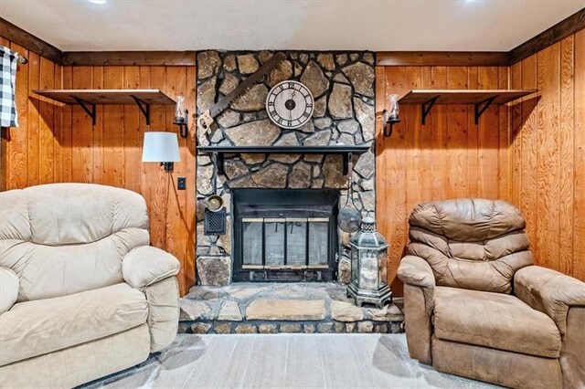 sitting room featuring a stone fireplace and wood walls