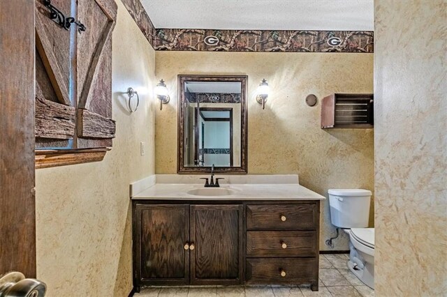 bathroom with a textured wall, toilet, vanity, a textured ceiling, and tile patterned flooring