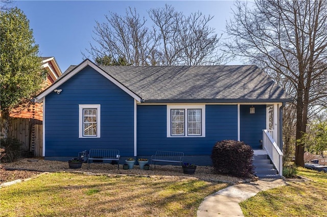 ranch-style home with roof with shingles, a front lawn, and fence