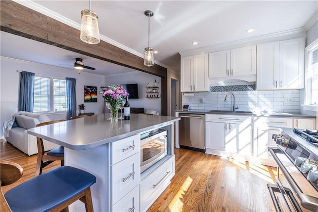 kitchen featuring a sink, stainless steel appliances, open floor plan, and white cabinetry