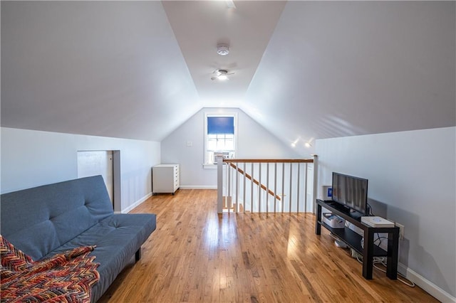 sitting room featuring wood finished floors, an upstairs landing, baseboards, and lofted ceiling