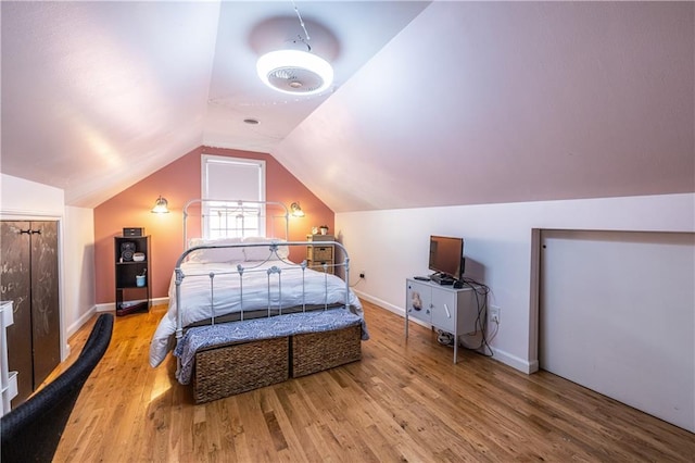 bedroom with baseboards, lofted ceiling, and wood finished floors