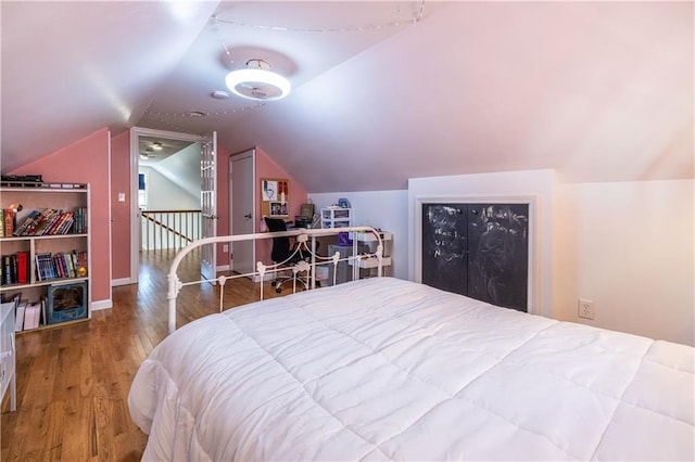 bedroom with vaulted ceiling and wood finished floors