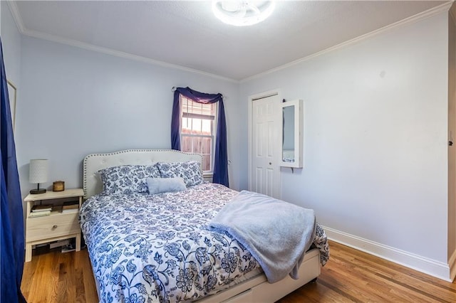 bedroom with wood finished floors, baseboards, and ornamental molding