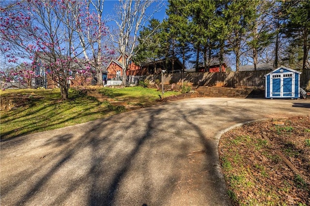 view of yard featuring a storage shed, an outdoor structure, and fence