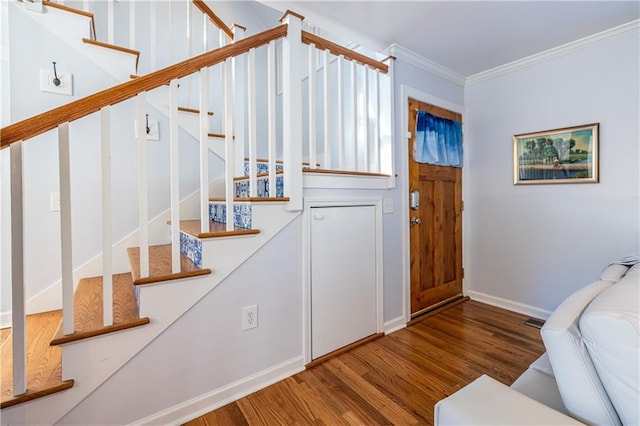 foyer entrance with stairway, wood finished floors, visible vents, baseboards, and crown molding