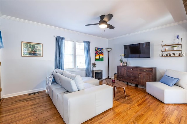 living room featuring light wood-type flooring, visible vents, baseboards, and ornamental molding