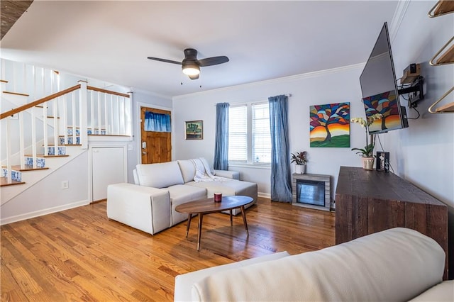 living area featuring crown molding, stairs, a ceiling fan, and wood finished floors