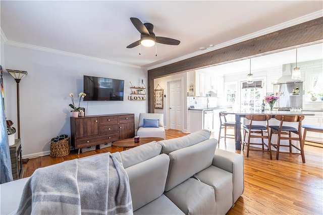 living area featuring a ceiling fan, light wood finished floors, and ornamental molding