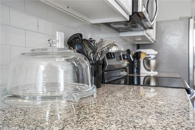 interior details featuring electric stove, light stone countertops, and backsplash