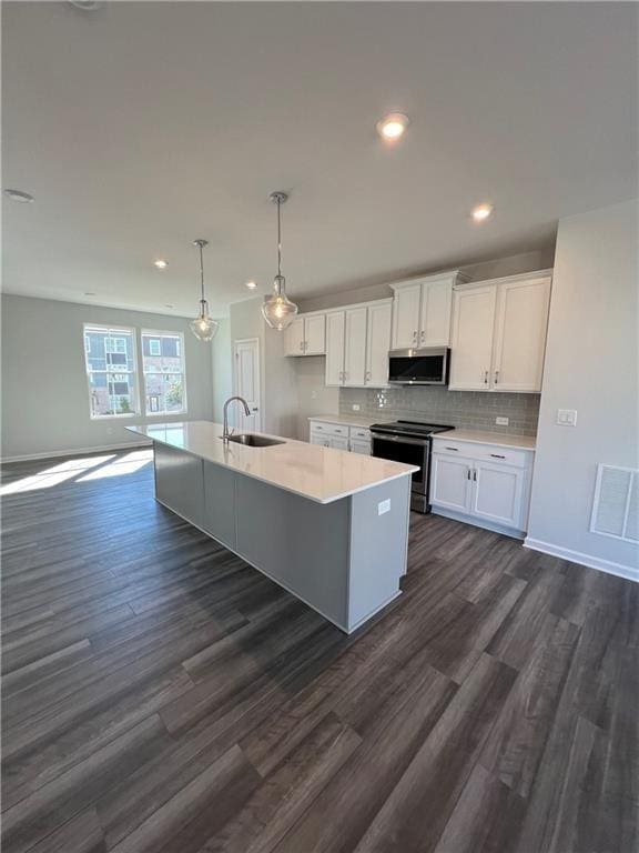 kitchen featuring sink, stainless steel appliances, white cabinets, a center island with sink, and decorative light fixtures