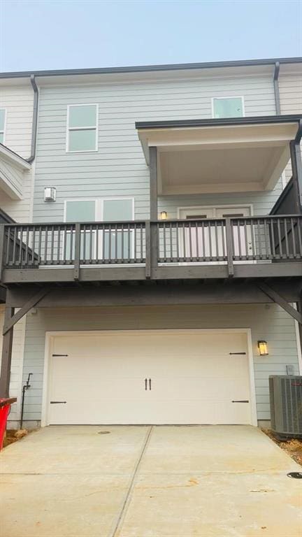 back of property featuring central AC, a balcony, and a garage