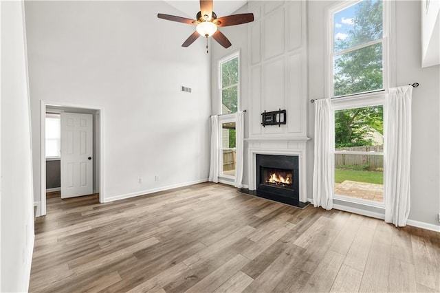 615 Rosedown Way, Alpharetta, GA 30022 - unfurnished living room with a towering ceiling, light wood-type flooring, a fireplace, and a ceiling fan