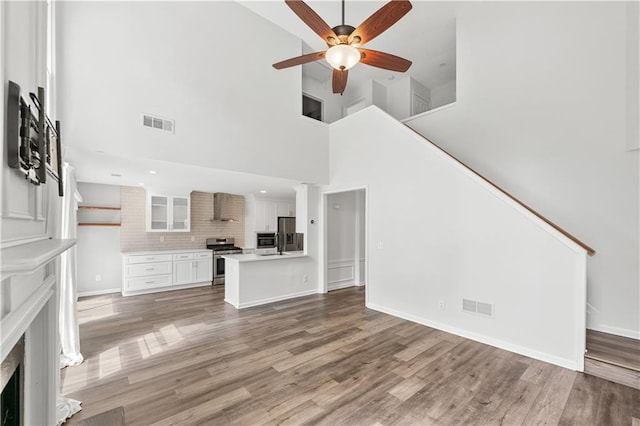615 Rosedown Way, Alpharetta, GA 30022 - unfurnished living room with a ceiling fan, light wood-style flooring, a towering ceiling, stairway, and a fireplace